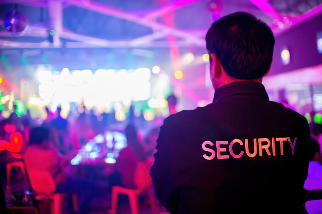 Back view of a security guard overseeing a vibrant event scene in Pretoria, with 'SECURITY' text on the back of his uniform
