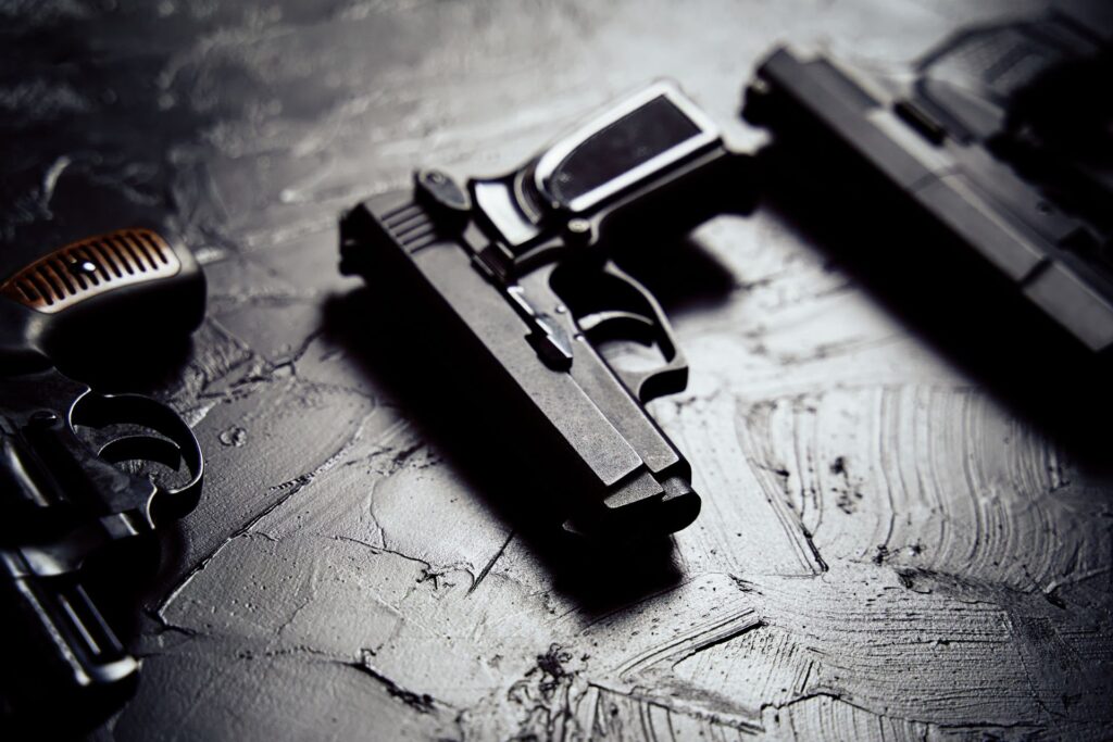 Dramatic close-up of a professional armed response handgun and handcuffs on a textured surface, emphasizing preparedness and defense capabilities