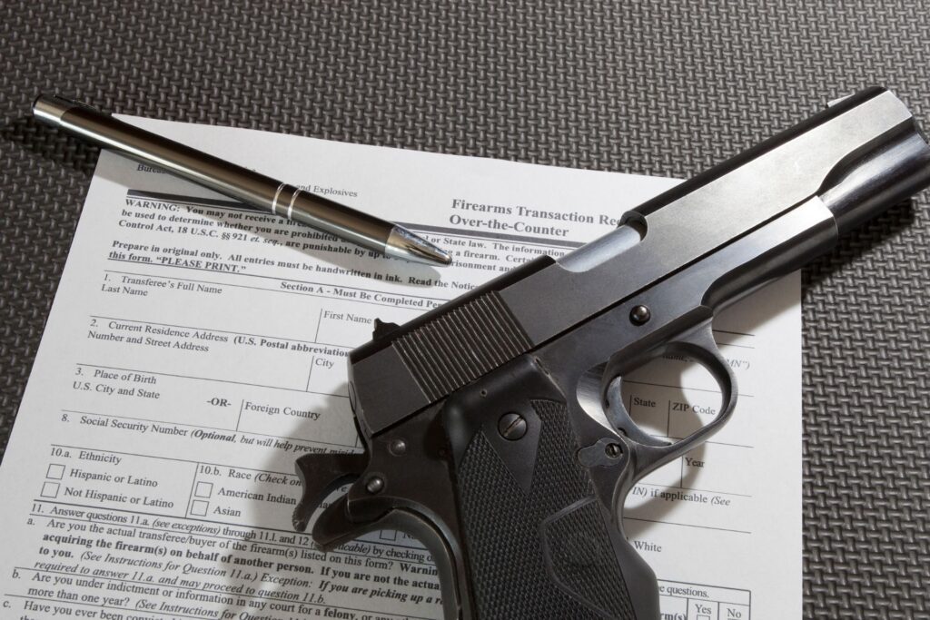 Handgun resting on a completed firearms transaction report, emphasizing the legal documentation required for firearm ownership