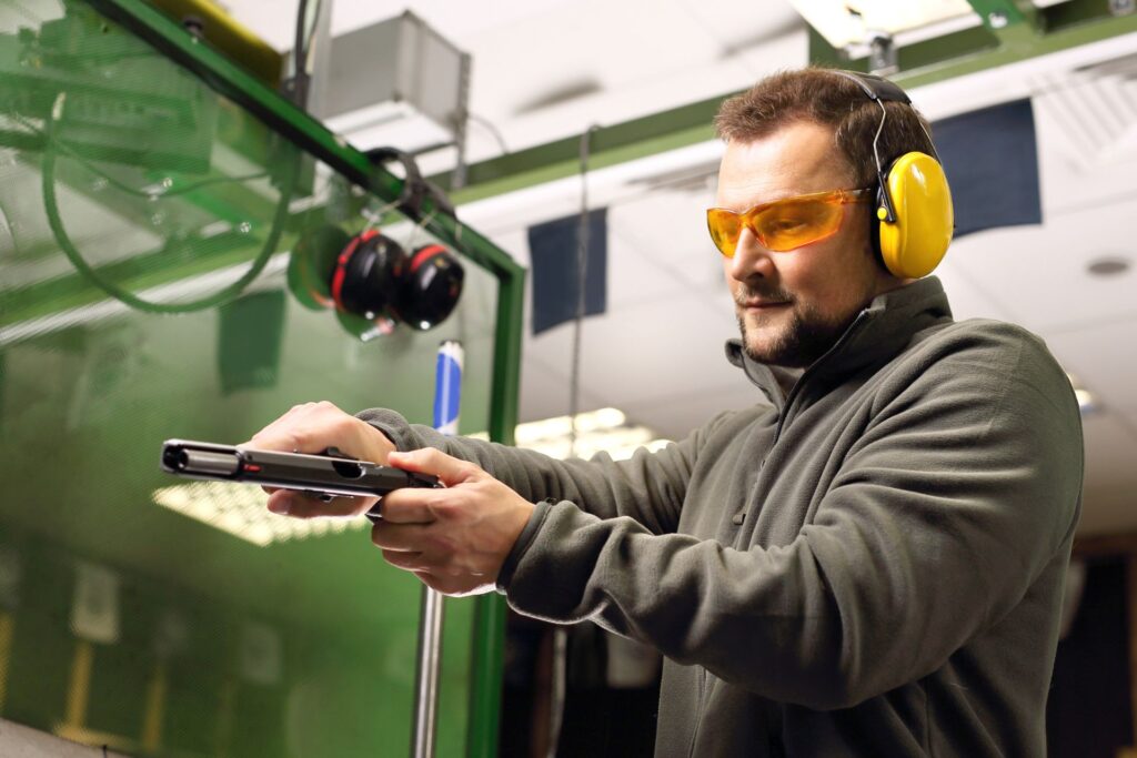 Man practicing shooting at a firing range, wearing safety gear, exemplifying the rigorous firearm training for security personnel