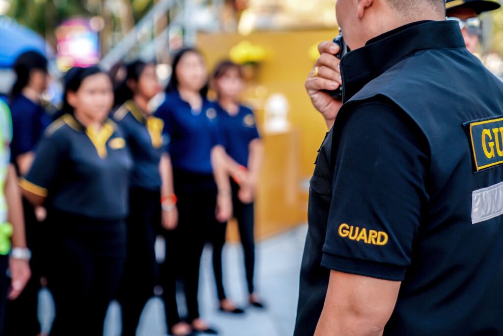 Security guard using a walkie-talkie to communicate during a team briefing with a group of attentive female staff in the background