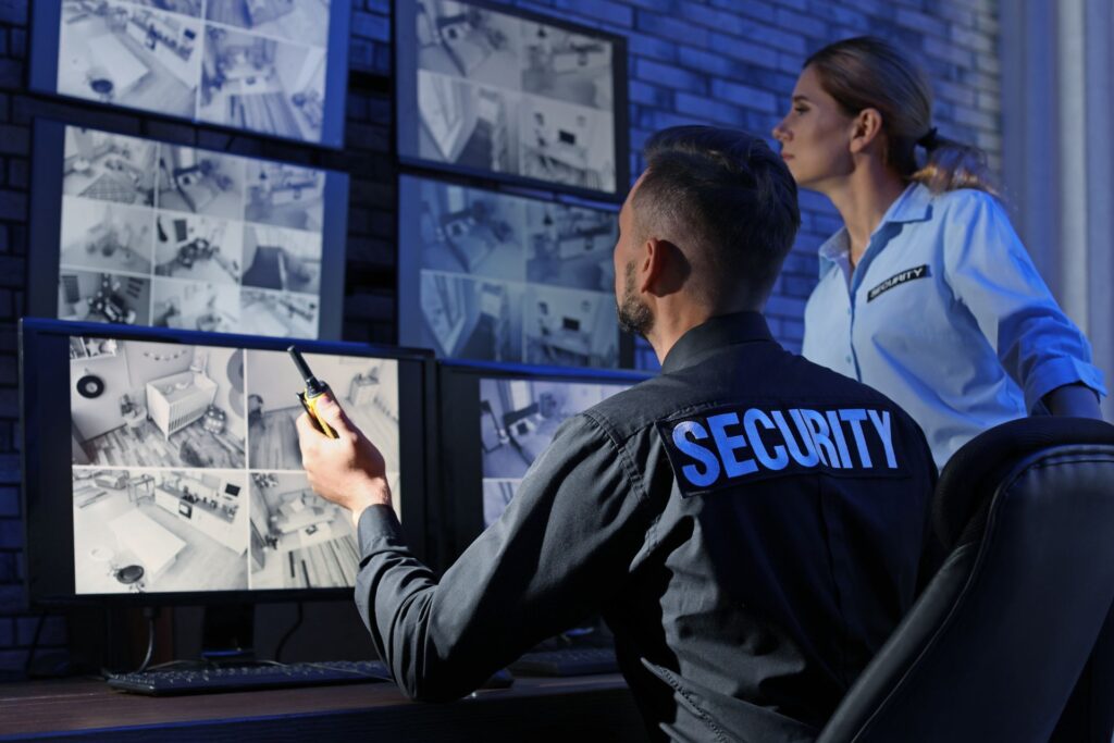 Security personnel monitoring multiple CCTV feeds in a control room, highlighting their active role in surveillance and security management